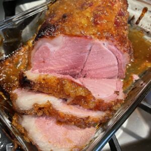 A roasted ham is sliced and ready for eating.