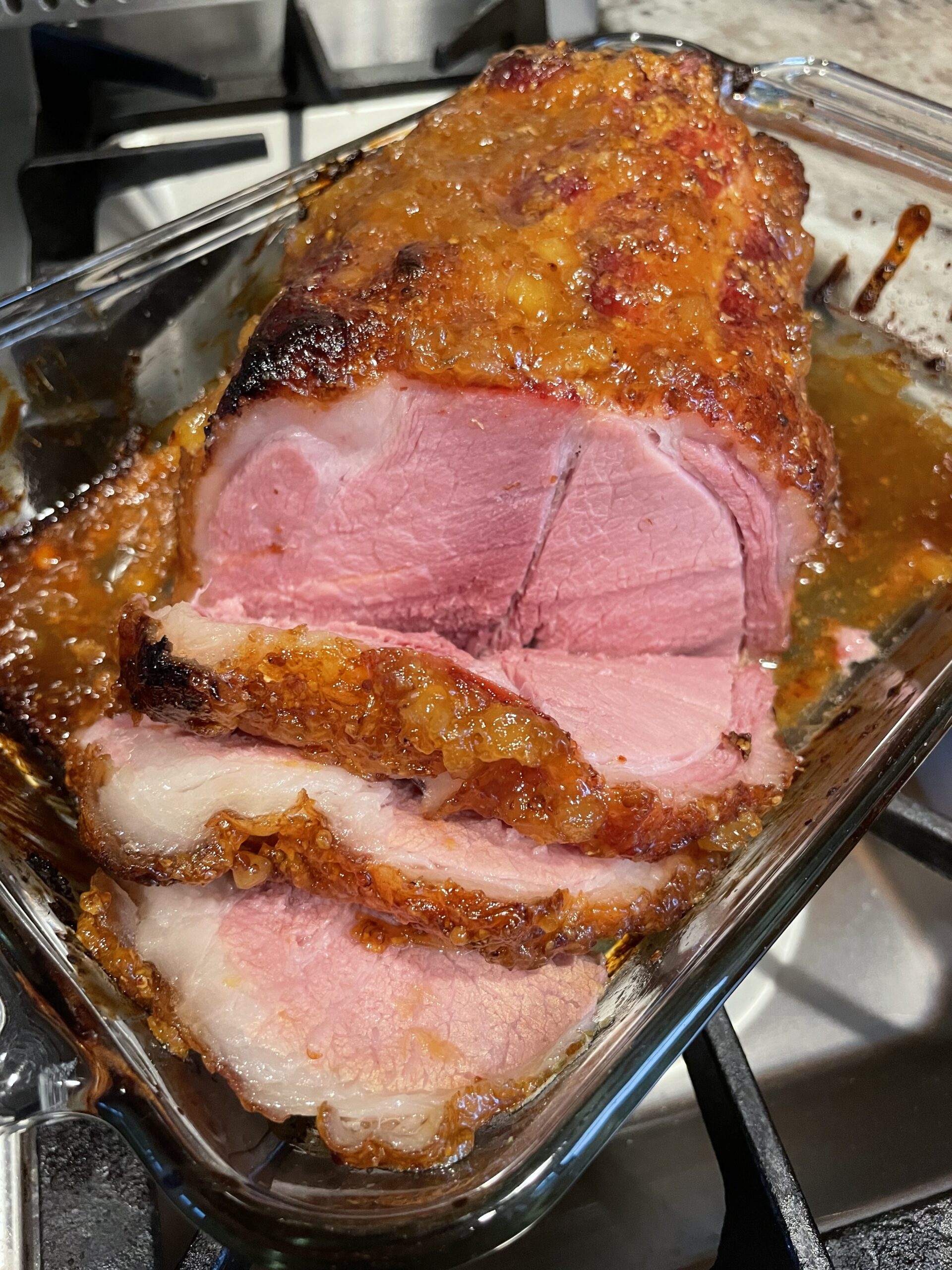 A roasted ham is sliced and ready for eating.
